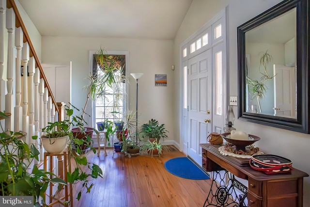 foyer with stairs, vaulted ceiling, baseboards, and hardwood / wood-style flooring