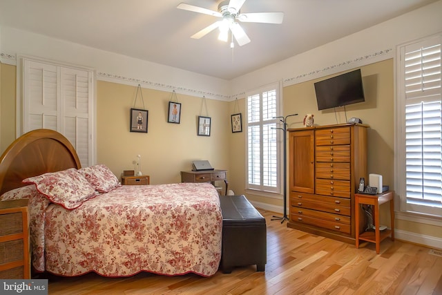 bedroom with light wood-style flooring, visible vents, baseboards, and ceiling fan