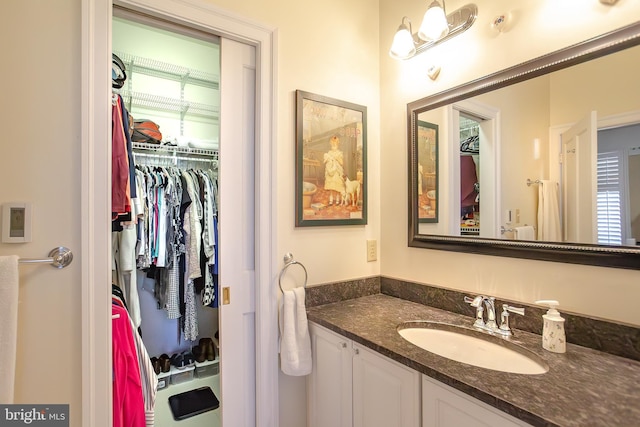 bathroom with a walk in closet and vanity