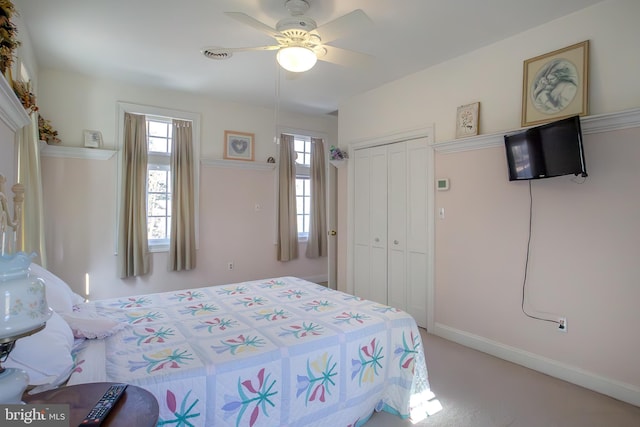 bedroom featuring a ceiling fan, a closet, light carpet, and baseboards