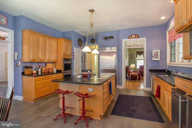 kitchen with appliances with stainless steel finishes, dark countertops, a center island, and dark wood-style floors