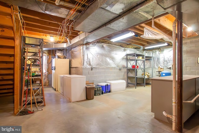 unfinished basement with freestanding refrigerator and refrigerator