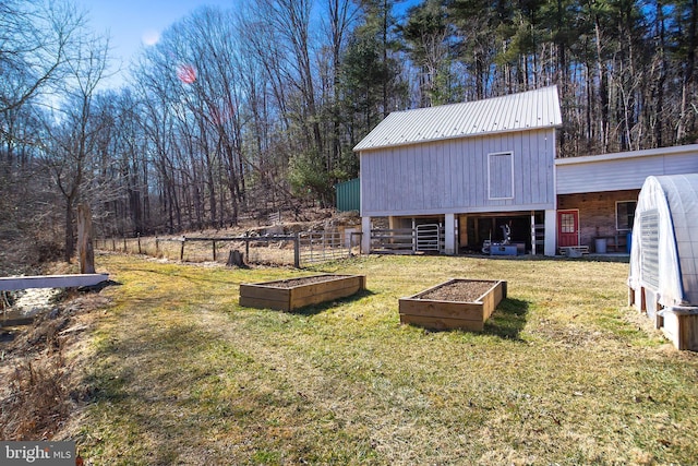 view of yard with fence, a vegetable garden, and an outdoor structure