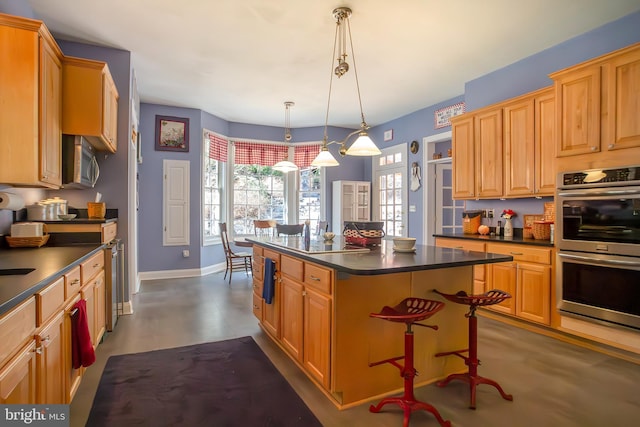 kitchen with a kitchen island, baseboards, appliances with stainless steel finishes, dark countertops, and decorative light fixtures