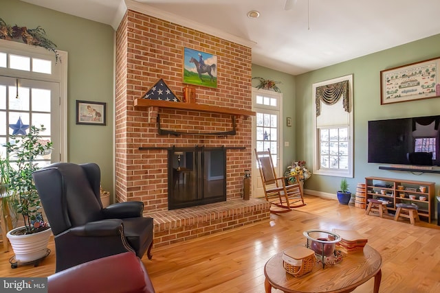 living area featuring baseboards, a fireplace, and hardwood / wood-style floors