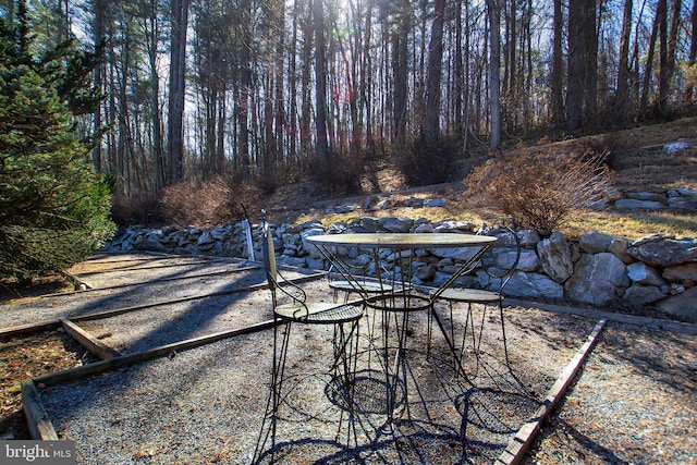 view of yard featuring outdoor dining area, a patio area, and a wooded view