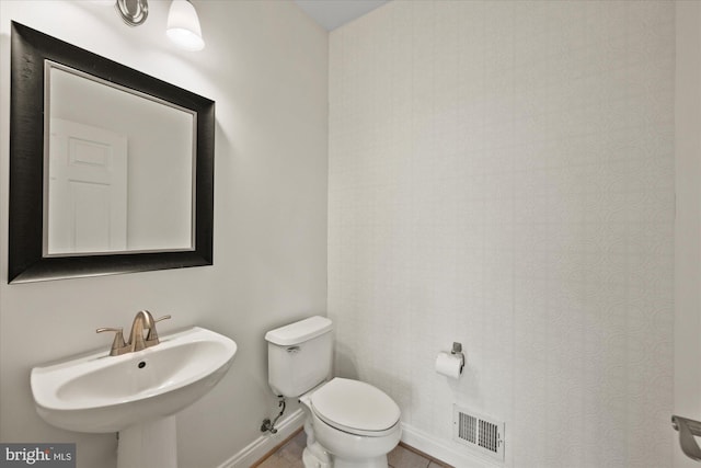 bathroom featuring visible vents, toilet, a sink, tile patterned flooring, and baseboards