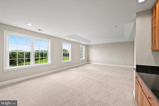 unfurnished living room featuring recessed lighting, light colored carpet, visible vents, baseboards, and a tray ceiling