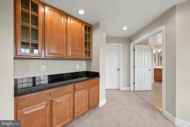 kitchen featuring light carpet, baseboards, glass insert cabinets, and recessed lighting