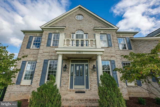 view of front of house featuring brick siding and a balcony