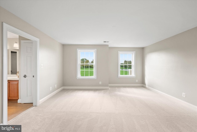 spare room featuring light carpet and baseboards