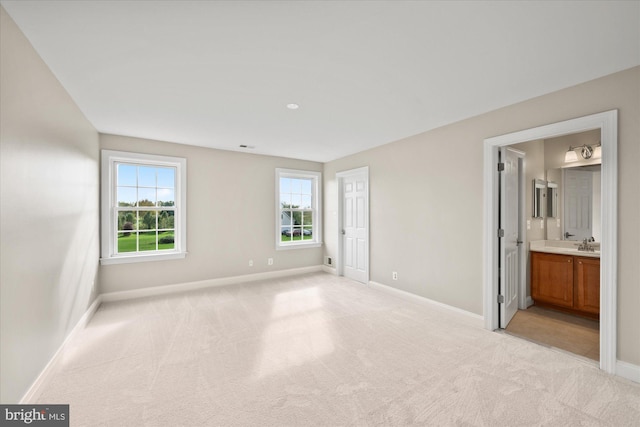 unfurnished bedroom with baseboards, a sink, and light colored carpet