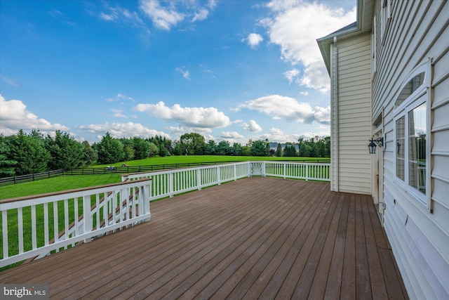 deck with a rural view, a lawn, and fence