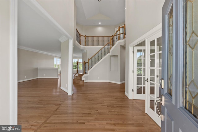 entryway with stairs, a high ceiling, wood finished floors, and baseboards