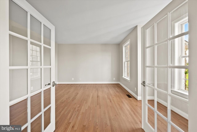 spare room featuring french doors, visible vents, baseboards, and wood finished floors