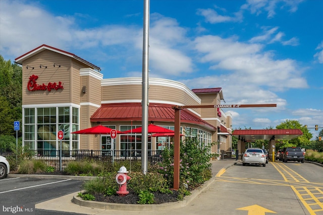 view of building exterior with uncovered parking and fence