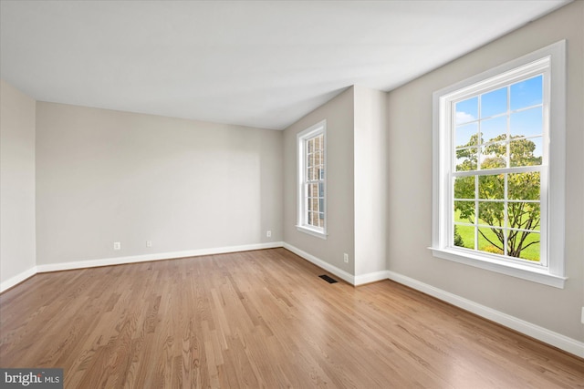 spare room featuring visible vents, light wood-style flooring, and baseboards