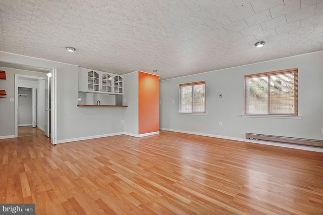 unfurnished living room featuring light wood-style floors, baseboards, and baseboard heating