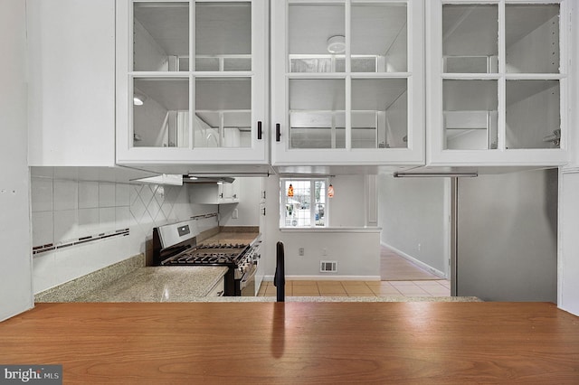 kitchen featuring visible vents, glass insert cabinets, backsplash, and stainless steel range with gas stovetop