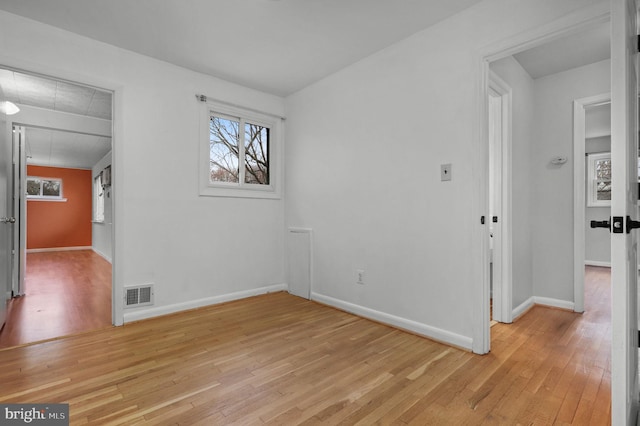 unfurnished room with visible vents, plenty of natural light, and light wood-style floors