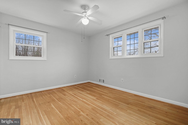 unfurnished room with plenty of natural light, baseboards, visible vents, and light wood finished floors