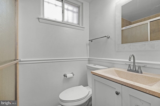 bathroom with tiled shower, toilet, and vanity