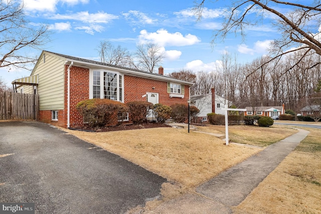 view of front of property with a front lawn, fence, brick siding, and a chimney