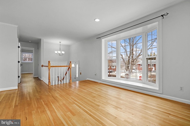 unfurnished room featuring wood finished floors, baseboards, and a chandelier