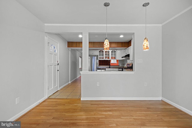 kitchen featuring light wood-type flooring, under cabinet range hood, stainless steel appliances, a peninsula, and baseboards