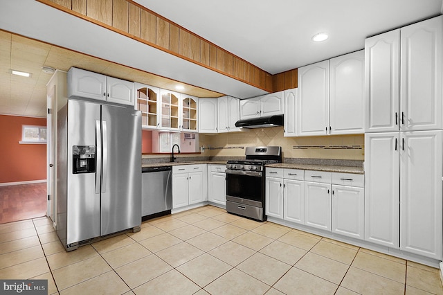 kitchen with glass insert cabinets, under cabinet range hood, appliances with stainless steel finishes, light tile patterned flooring, and a sink