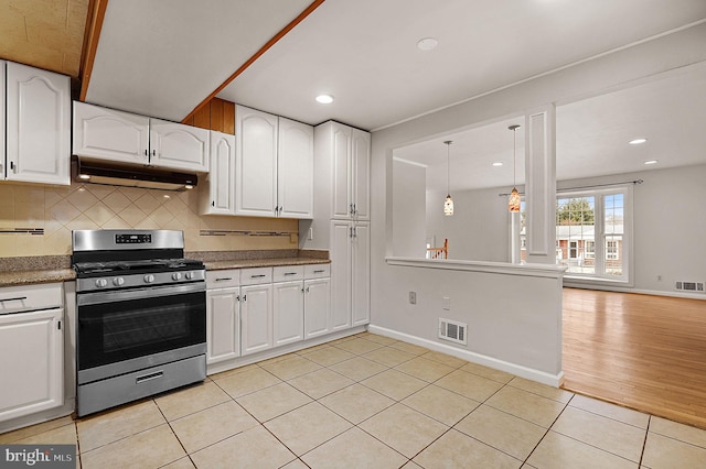 kitchen with tasteful backsplash, visible vents, under cabinet range hood, gas range, and light tile patterned flooring