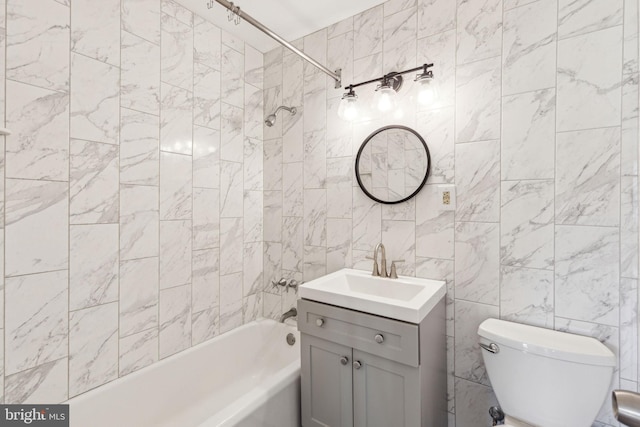 bathroom featuring toilet, washtub / shower combination, tile walls, and vanity