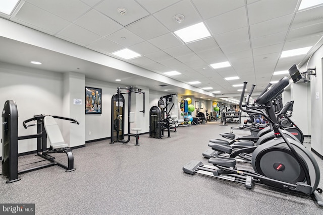 workout area with a paneled ceiling and baseboards