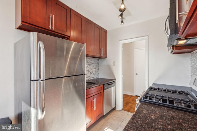 kitchen featuring light tile patterned floors, appliances with stainless steel finishes, decorative backsplash, and dark stone countertops