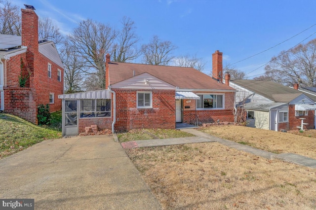 bungalow-style house featuring a front lawn, brick siding, and a chimney