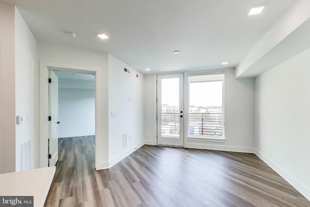 unfurnished room featuring recessed lighting, wood finished floors, visible vents, and baseboards