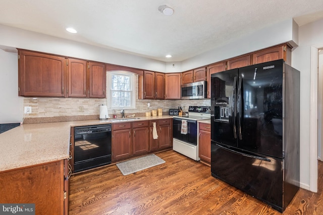 kitchen featuring black appliances, tasteful backsplash, dark wood-style flooring, and a sink