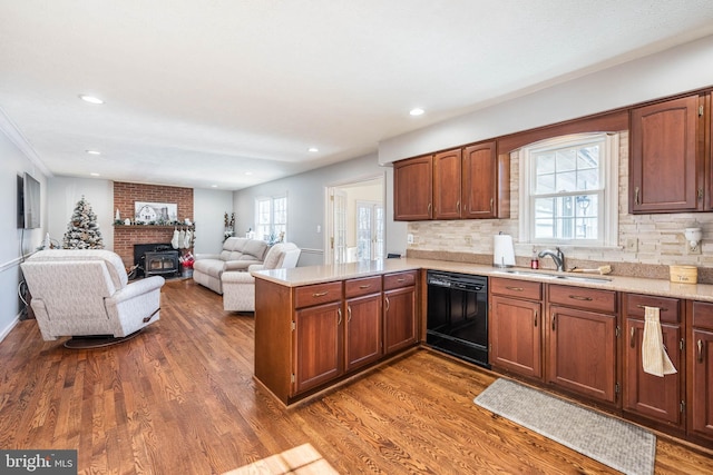 kitchen with dishwasher, a peninsula, wood finished floors, and a sink