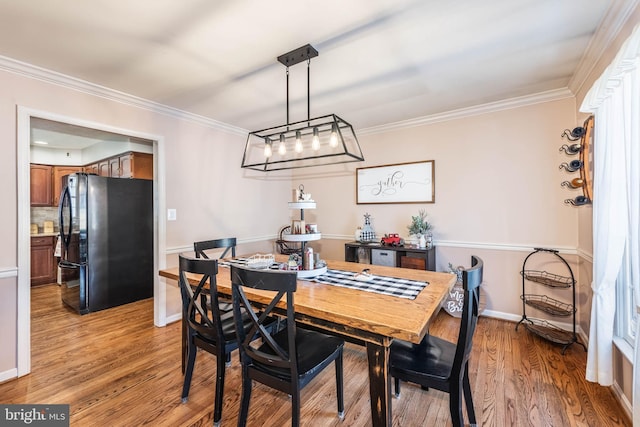 dining space with light wood finished floors, baseboards, and crown molding