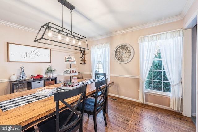 dining room with ornamental molding, wood finished floors, visible vents, and baseboards