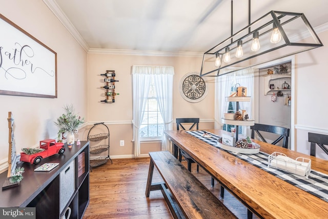 dining room with baseboards, ornamental molding, and wood finished floors