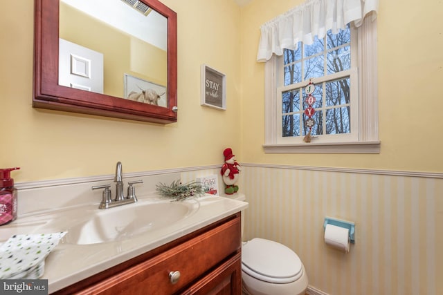 bathroom featuring wainscoting, visible vents, vanity, and toilet