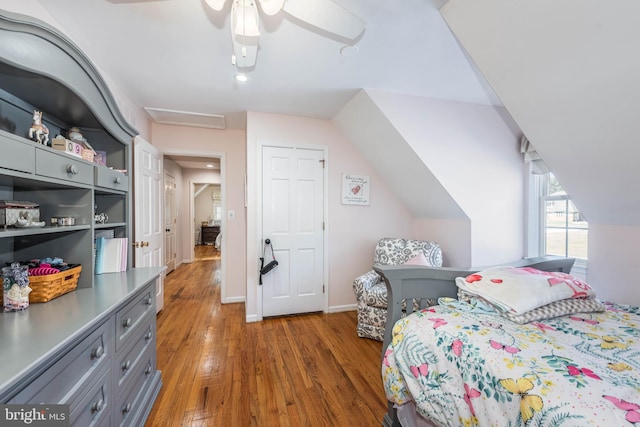 bedroom with attic access, baseboards, a ceiling fan, wood finished floors, and vaulted ceiling