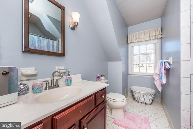 bathroom with baseboards, vaulted ceiling, vanity, and toilet