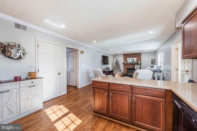 kitchen featuring a peninsula, wood finished floors, visible vents, light countertops, and a brick fireplace