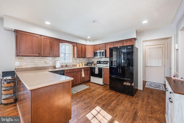 kitchen featuring a peninsula, a sink, backsplash, dark wood-style floors, and black appliances