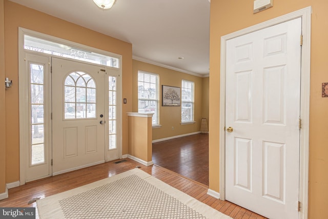 foyer featuring baseboards, crown molding, and hardwood / wood-style flooring