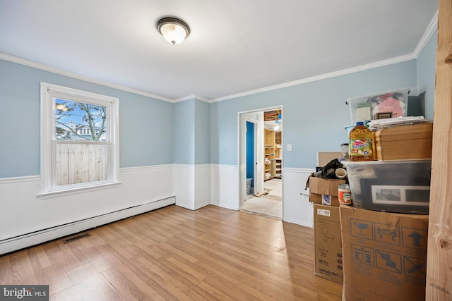 interior space with wainscoting, ornamental molding, a baseboard radiator, and wood finished floors