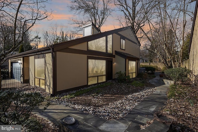 view of side of home featuring a garage and stucco siding