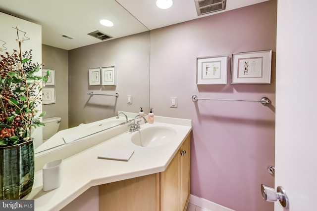 bathroom with toilet, visible vents, and vanity